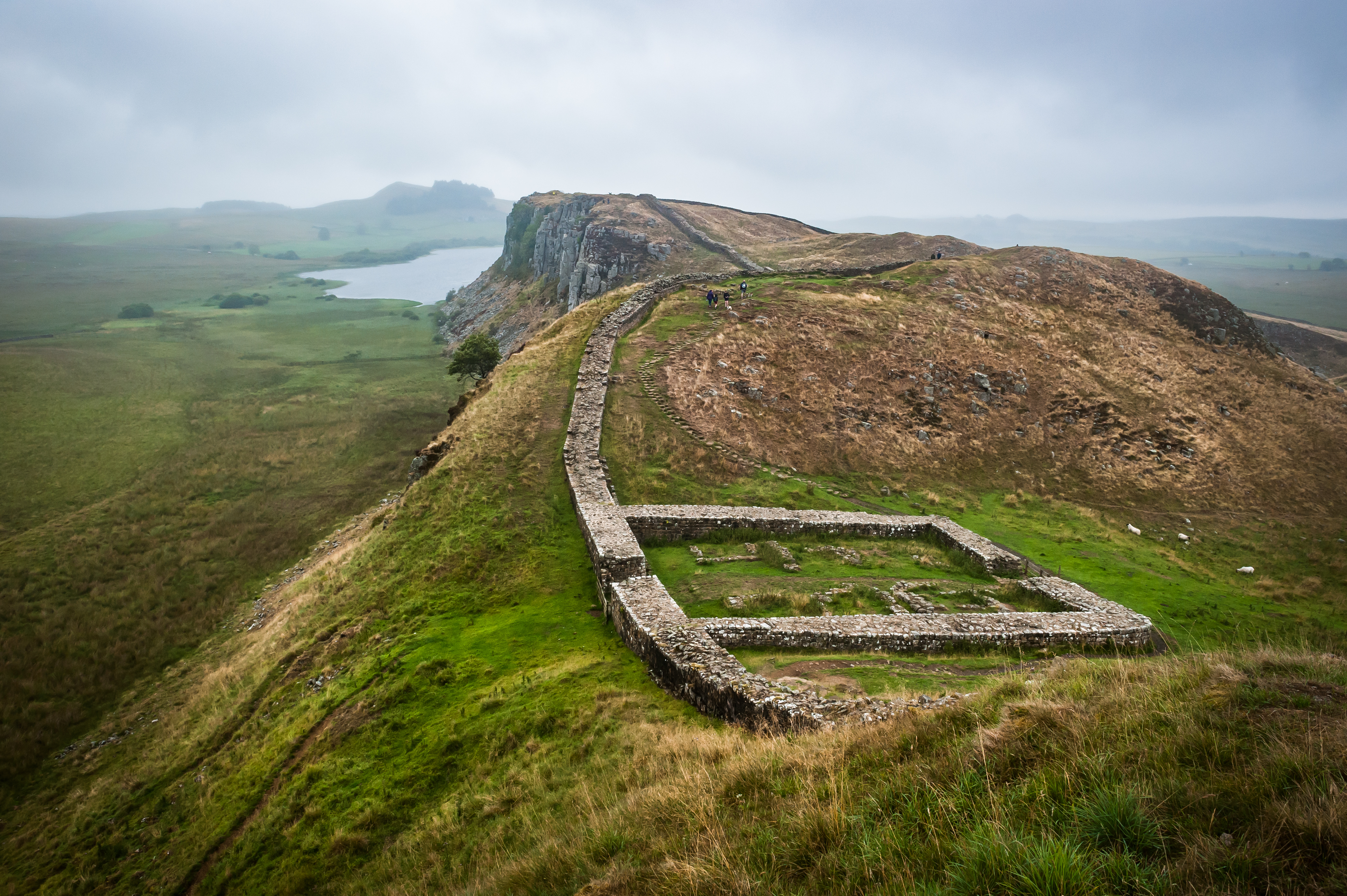overcast scene of a low wall running into the distance towards cliffs and the sea