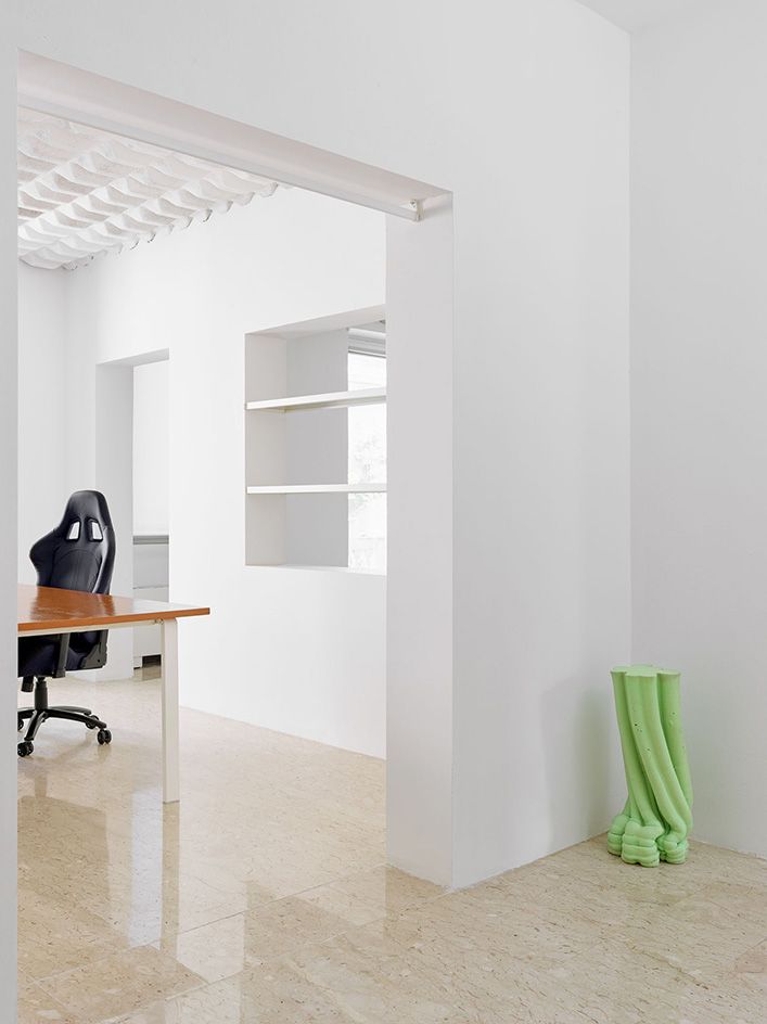 Desk with chair, doorway, green statue in right corner of doorway 