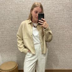 Woman wears suede jacket, white T-shirt, white linen trousers