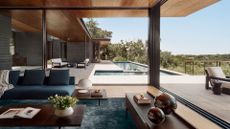 A bright and airy living room with floor to ceiling windows opening onto the outdoor deck and pool