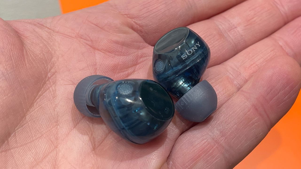 A blue pair of Sony WF-C710N in-ear headphones in the palm of somebody's hand.