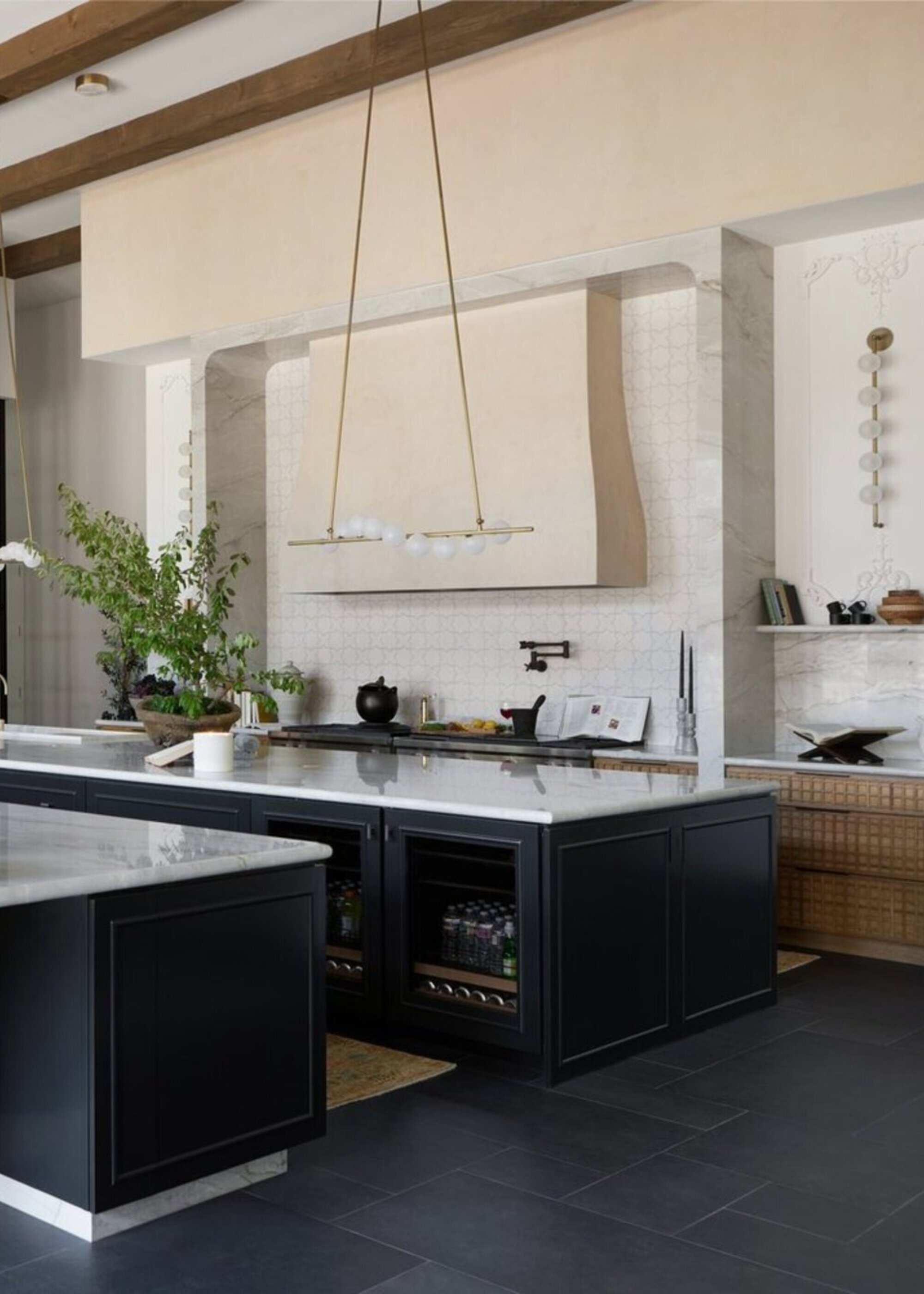 A kitchen with two islands and a large range oven in an alcove encased in stone