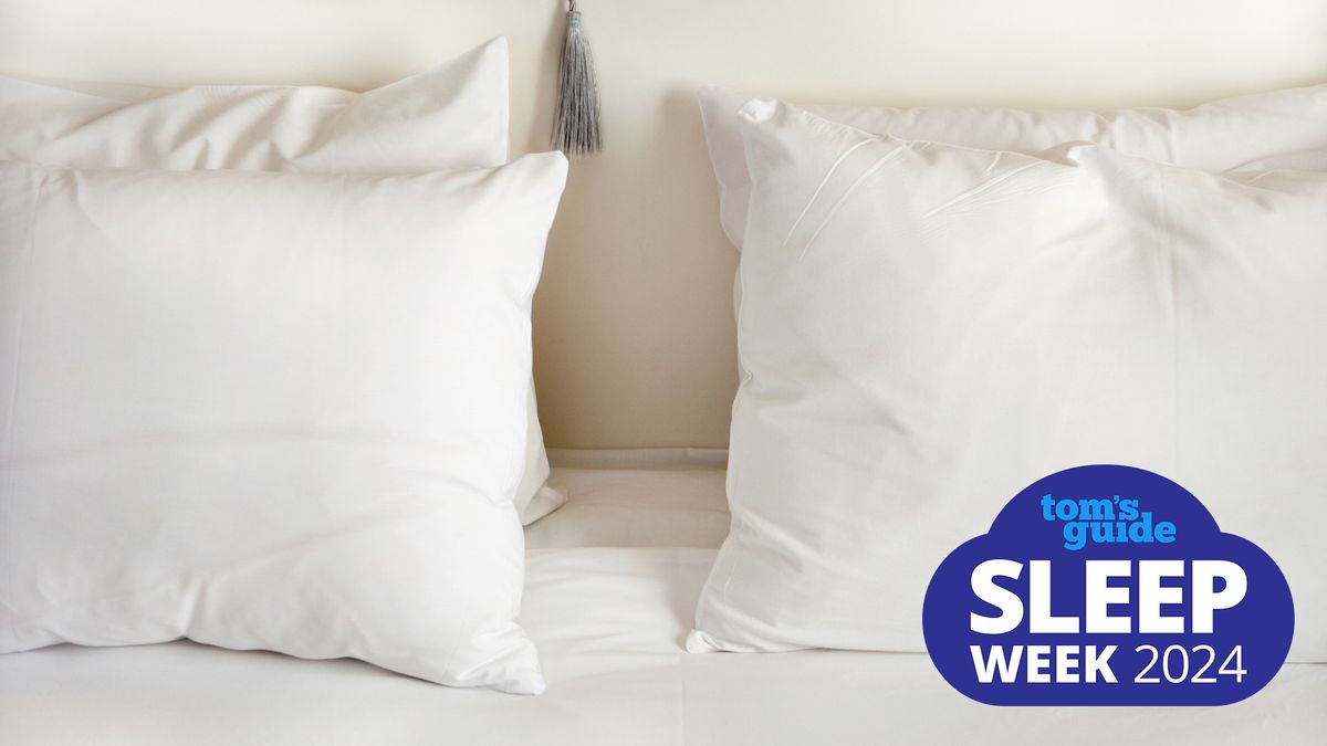 Four white pillows stacked for sleeping upright on a bed