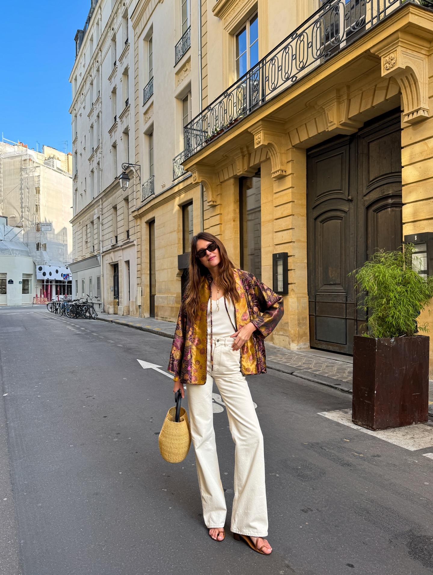 Woman wearing jeans, a jacket, and a raffia bag