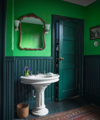 Green walls and dark green door, white sink