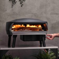 Witt pizza oven on a table with a hand adjusting the heat