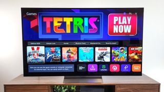 The LG C4 OLED, our pick for the best 75-inch TV for gaming, displaying the games section of LG's webOS smart platform in a living room setting