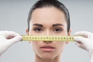 A woman's face is measured by a tape measure.