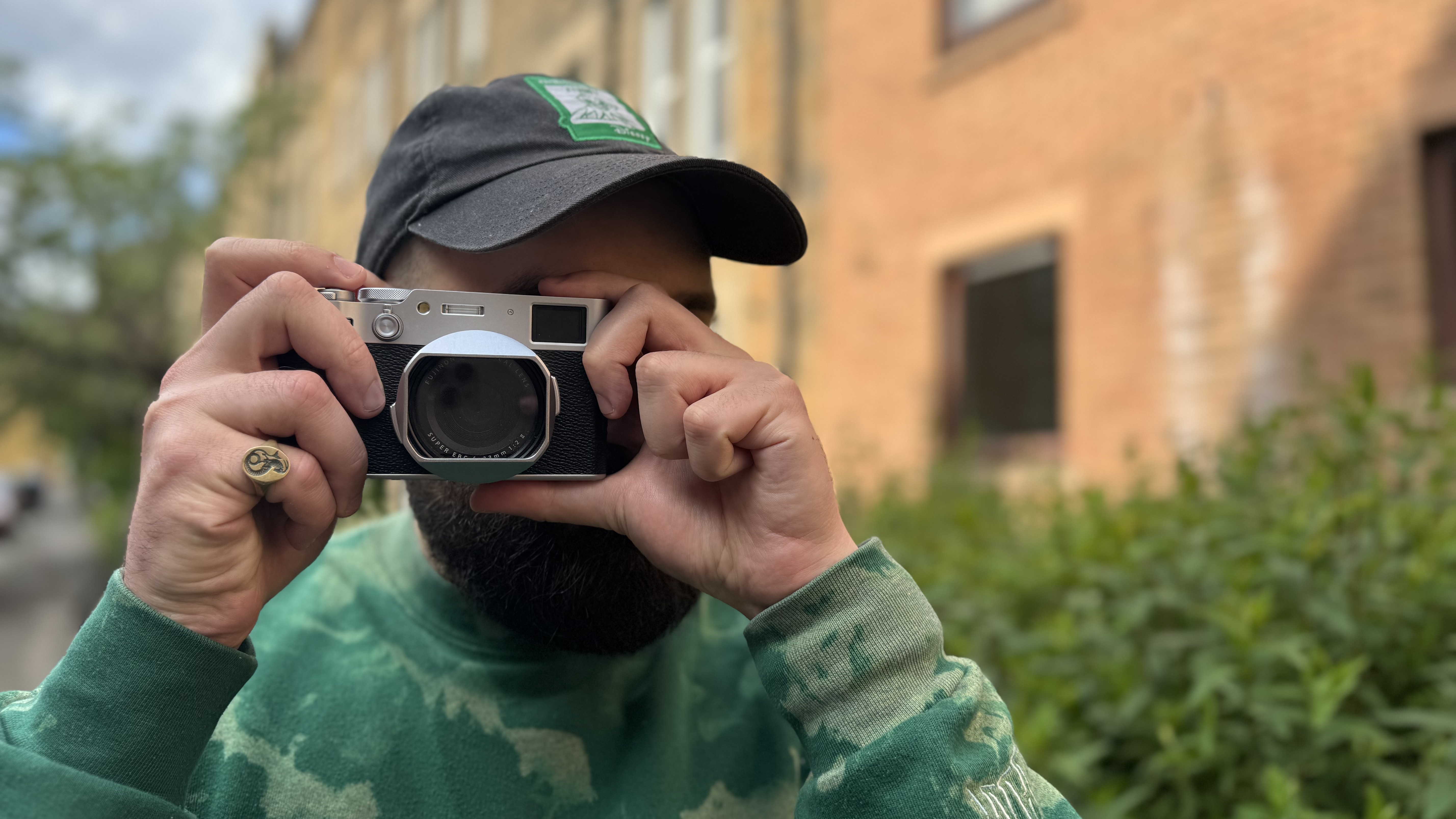 A man in a green jumper taking photos with the Fujifilm X100VI