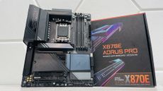 Gigabyte X870E Aorus Pro motherboard with the SSD heatsinks detached and on a light desk.