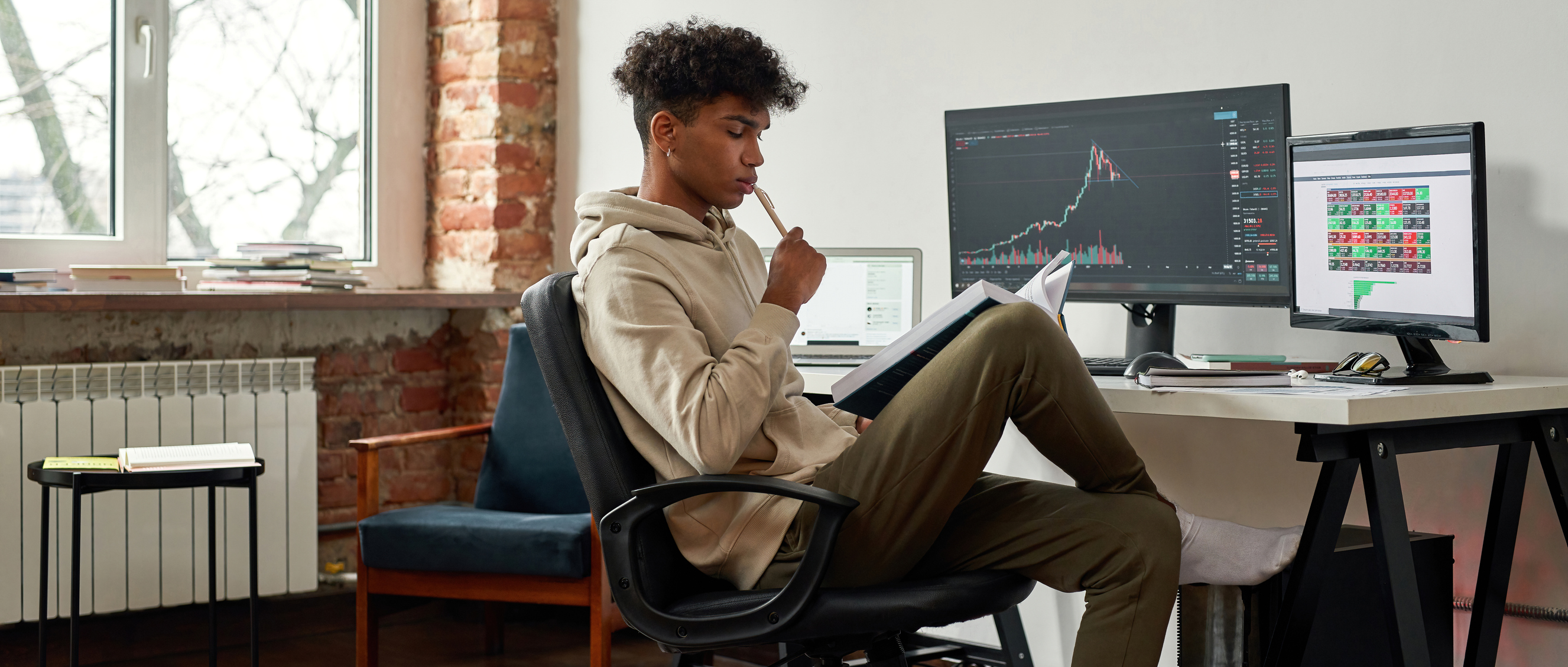 Young investor sitting by a laptop with a financial chart showing