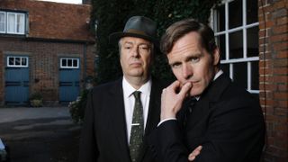 Roger Allam in a dark suit and hat as DCI Fred Thursday with Shaun Evans in a dark suit as DS Endeavour Morse in Endeavour season 9. 