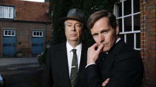 Roger Allam in a dark suit and hat as DCI Fred Thursday with Shaun Evans in a dark suit as DS Endeavour Morse in Endeavour.