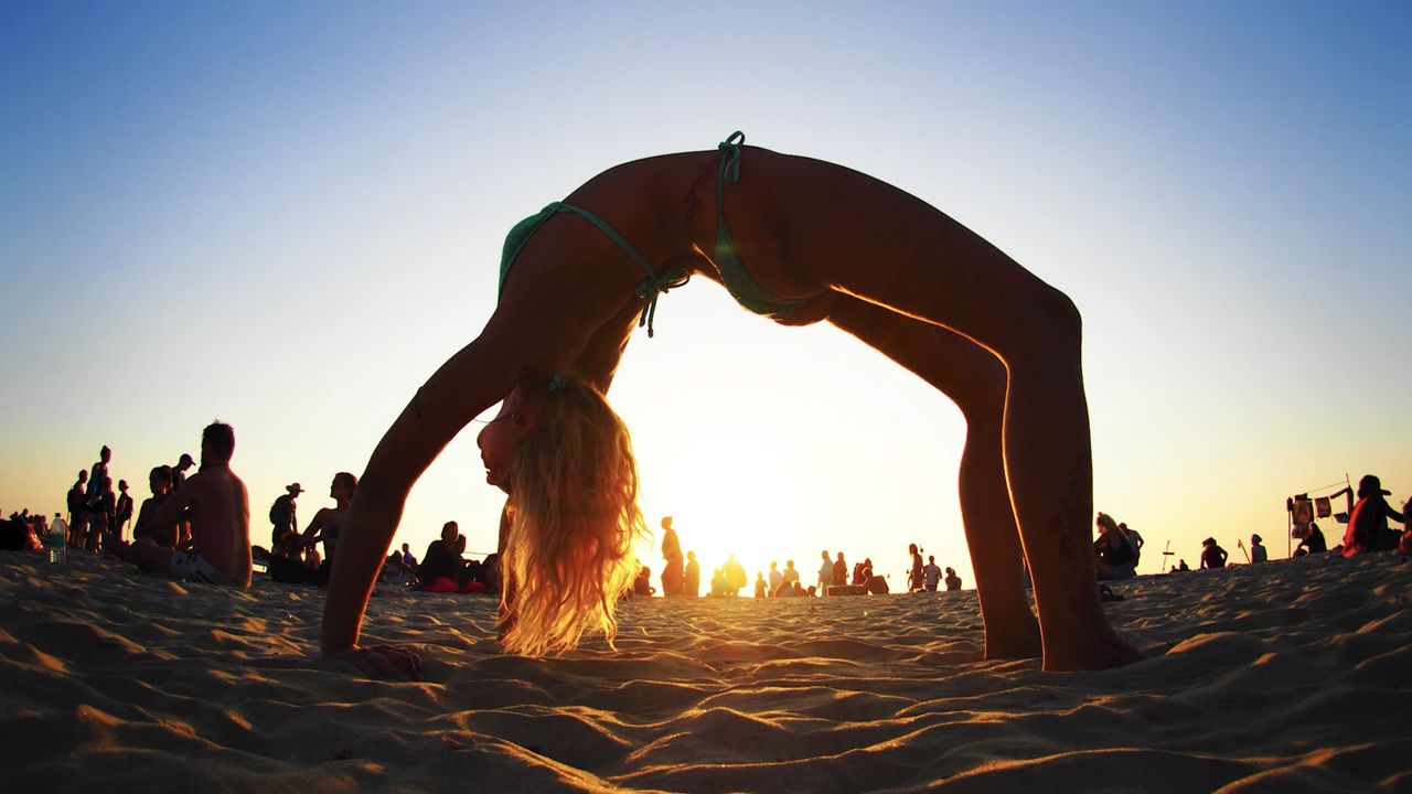 Fisheye lens shot of a woman doing a yoga pose on a beach