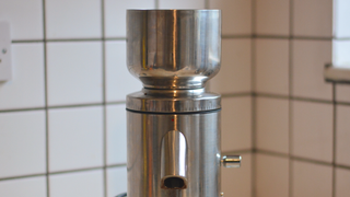 Image of the Aarke Coffee System – a stainless steel coffee bean grinder and drip coffee maker – positioned on a kitchen counter