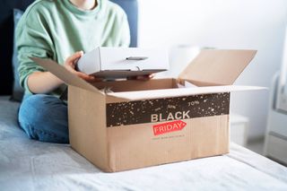 Woman opening a box from Black Friday shopping event.