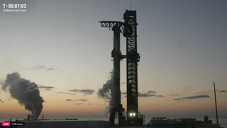 A SpaceX Starship rocket and Super Heavy booster stand ready for launch at dawn for Starship Flight 5.