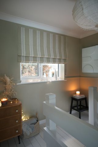 A stairway with Christmas decorations and the windowsill and a roman blind in the window