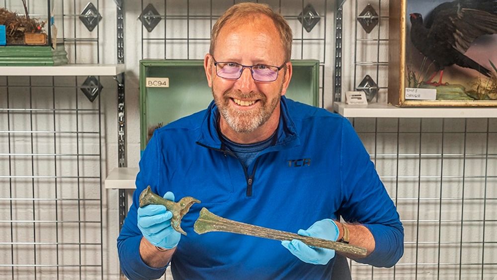 A man holds a sword inside a musem. 