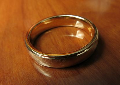 A gold wedding band on a wooden table