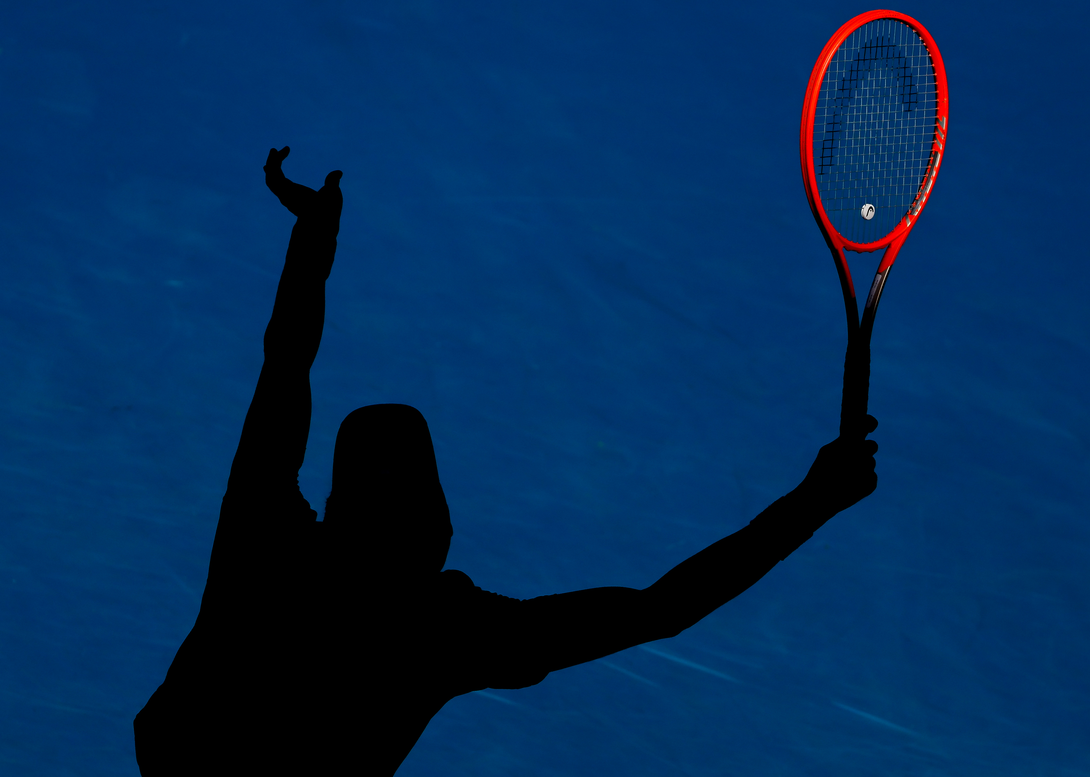 Shadow of a tennis player on the court holding a red racket