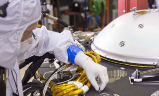 A spacecraft specialist in a clean room at Lockheed Martin Space Systems in Denver, where the InSight lander is being tested, affixes a dime-size chip onto the lander deck in November 2015. A second microchip will be added in 2018.