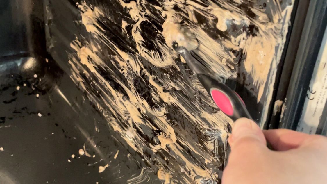 Cleaning an oven with baking soda and using a toothbrush to apply