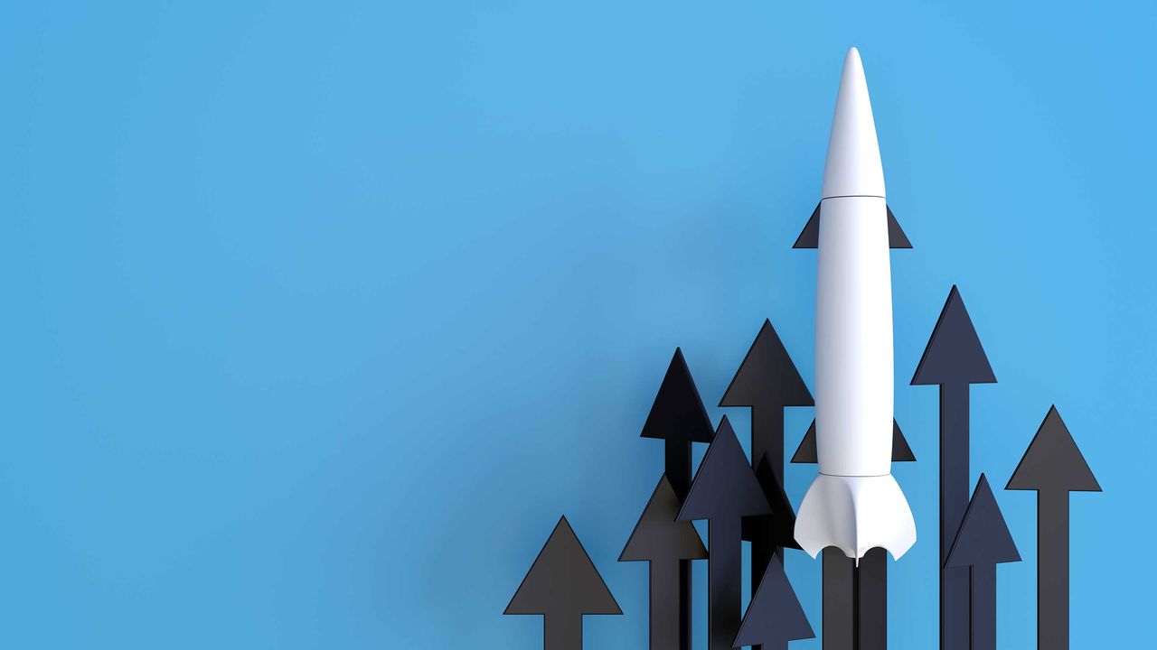 A white rocket moving higher against a background of arrows also moving higher, all against a blue background