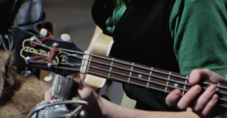 A screengrab showing the headstock of Paul McCartney's 1961 Hofner bass in the 2022 film Get Back. The image shows the use of a guitar tuning peg for the bass guitar's A string.