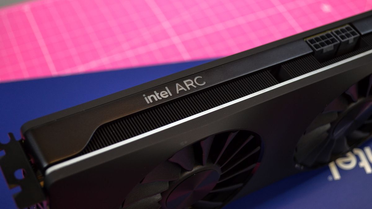 An Intel Arc A750 graphics card on a pink desk mat next to its retain packaging