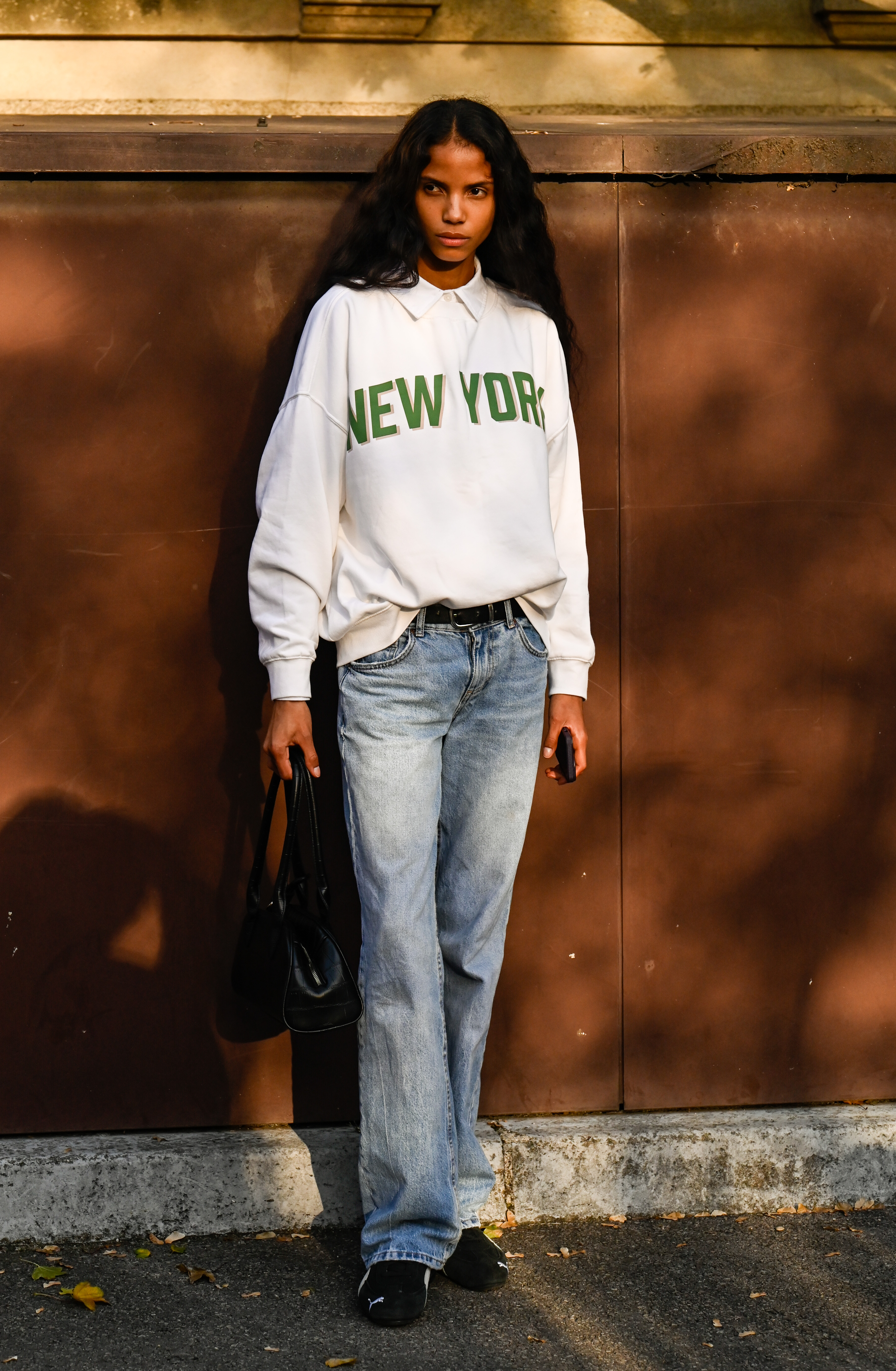 PARIS, FRANCE - OCTOBER 05: Model Josefa Santos wearing a white and green shirt, light blue jeans, black belt, black shoes and black bag outside the Jean Paul Gaultier show during the Womenswear Spring Summer 2026 as part of Paris Fashion Week on October 05, 2025 in Paris, France. (Photo by Daniel Zuchnik/Getty Images)