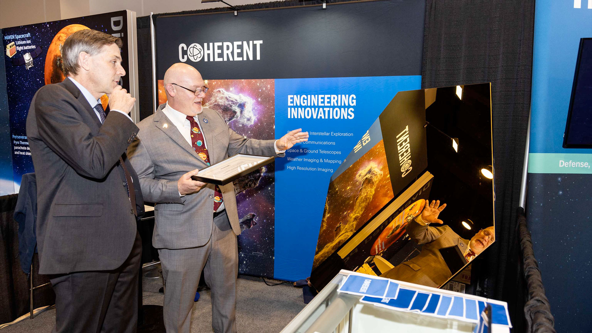 two men in suits look at a model of a telescope mirror