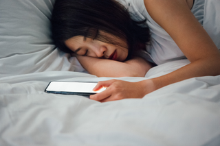 woman in bed with phone in hand