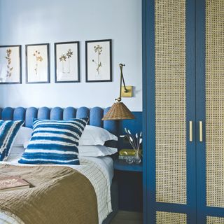 A light blue painted bedroom with dark blue headboard and matching wardrobe with rattan inserts on the door