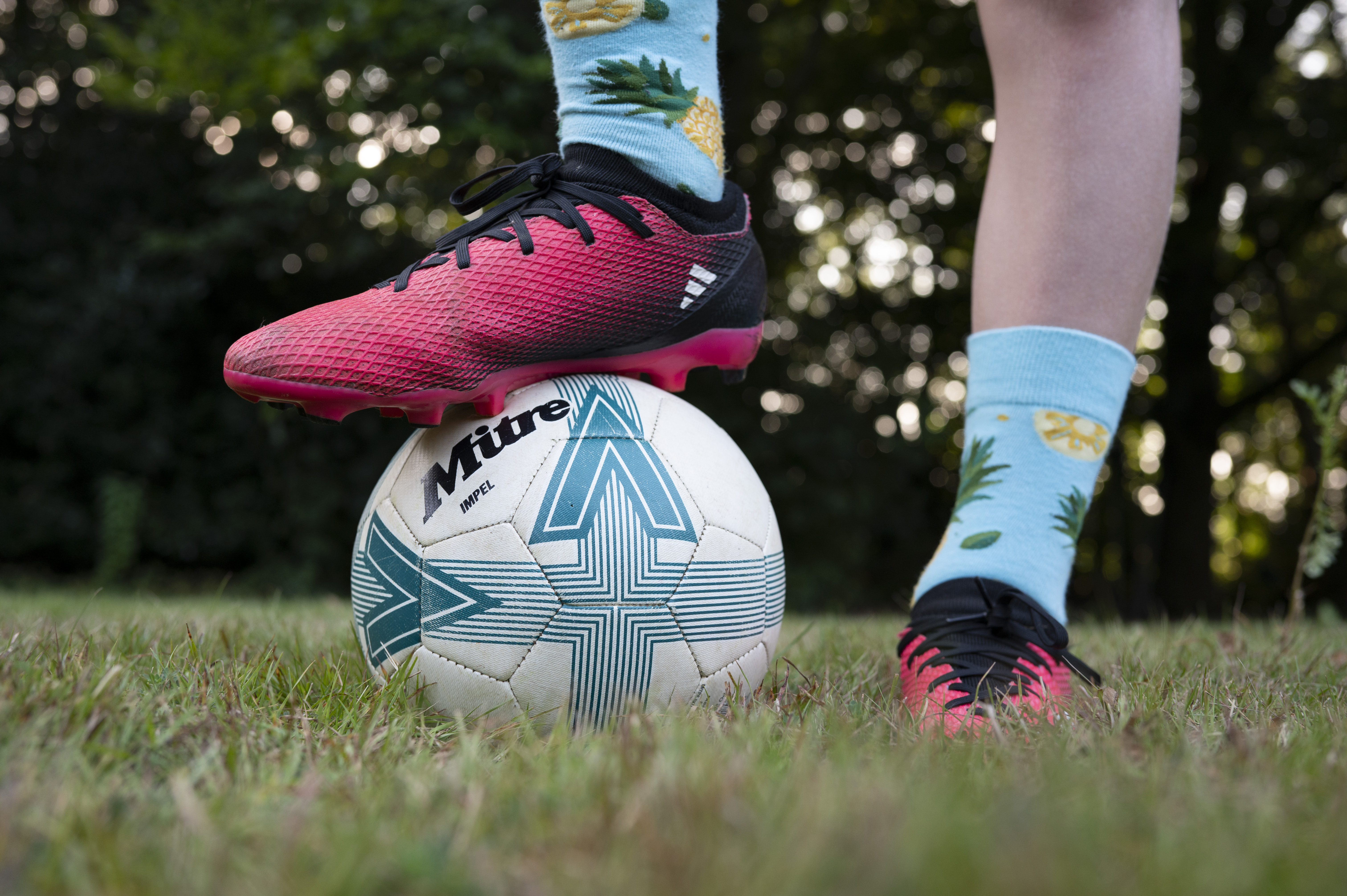 Closeup of a footballer's feet, with one foot standing on top of a ball