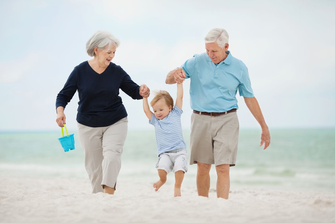 Grandparents playing with a grandson on a beach. 