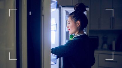 Woman eating late at night looking through fridge under light