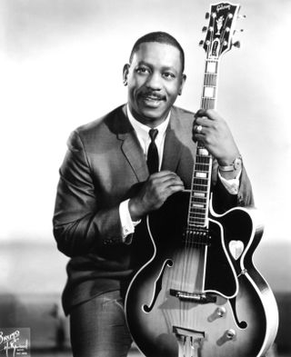 Jazz guitarist Wes Montgomery poses for a portrait holding a Gibson hollow body electric guitar during his sting on Verve Records in 1965.
