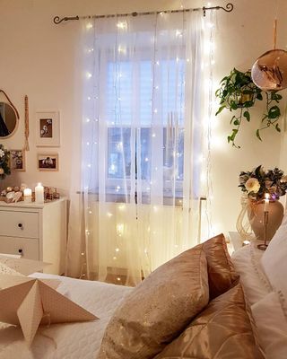 pretty bedroom with a white voile and fairy lights hanging over the window