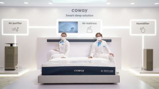 Two people sit on the Coway Smart Care Air Mattress