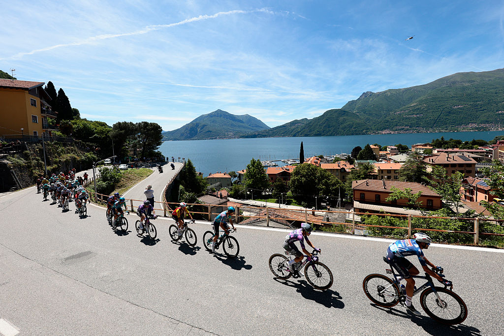 The pack rides past the town Bellano on the shore of Lake Como during the 18th stage of the 108th Giro d'Italia cycling race of 144kms from Morbegno to Cesano Maderno on May 29, 2025. (Photo by Luca Bettini / AFP)