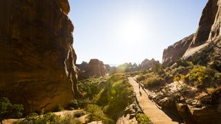 A woman trail running a scenic trail in Arches National Park