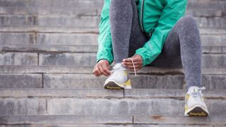 Runner sitting on steps tying shoelace