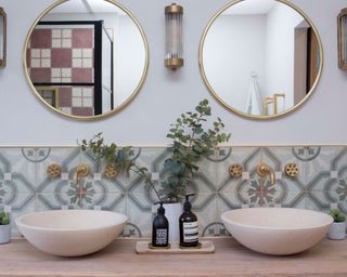 Homely bathroom with reclaimed, Mediterranean tiles on backsplash, double bowl sinks, and double round wall mirrors