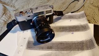 Leica M2 with a 50mm lens attached, placed on top of film negatives