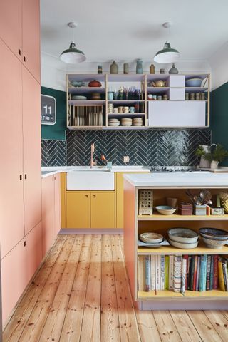 Modern kitchen with pink and yellow cabinets, island, open shelving and green tile backsplash