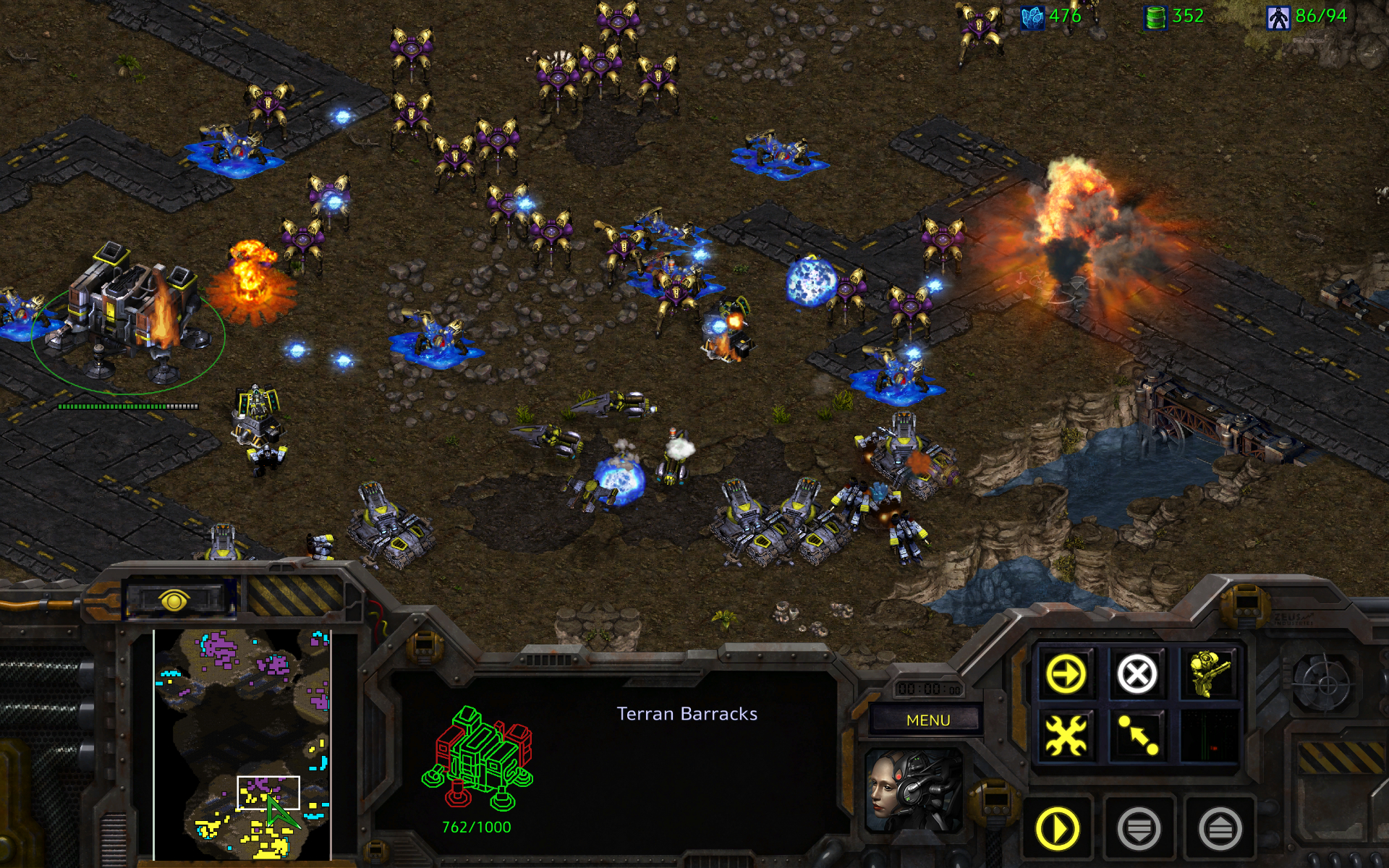 StarCraft battle: blue-and-gold units clash across a rocky base as explosions flare; the interface shows a Terran Barracks, evoking tense strategy and chaos.