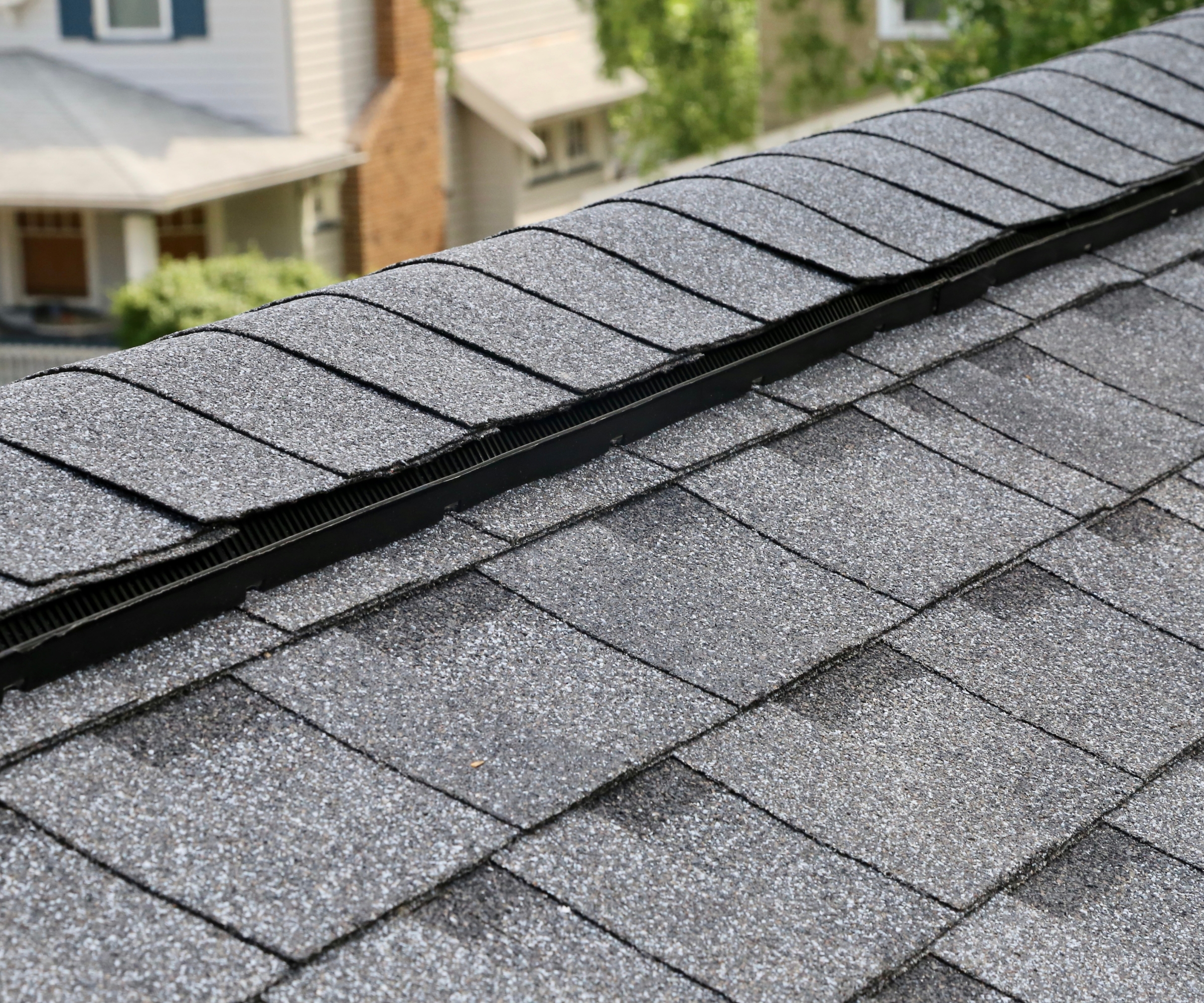 Composite shingles roofing close-up, looking down, with other blurred houses in the background