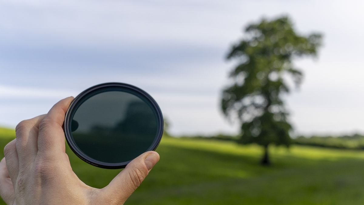 The Kenko Pro1D NDX3-450 filter held in a female hand with green grass in the background