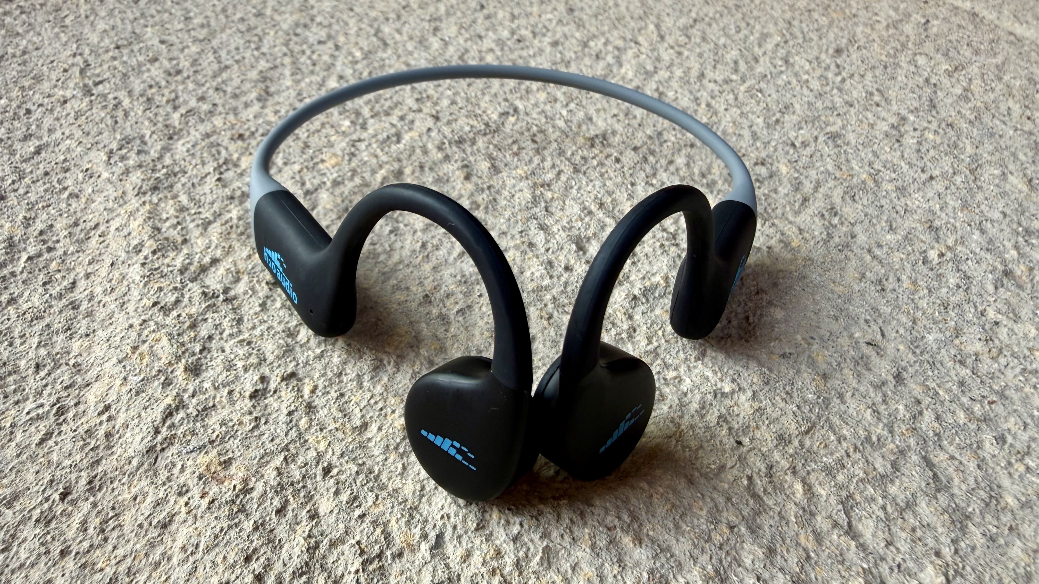 The h2o audio tri run bone conduction headphones on a stone surface